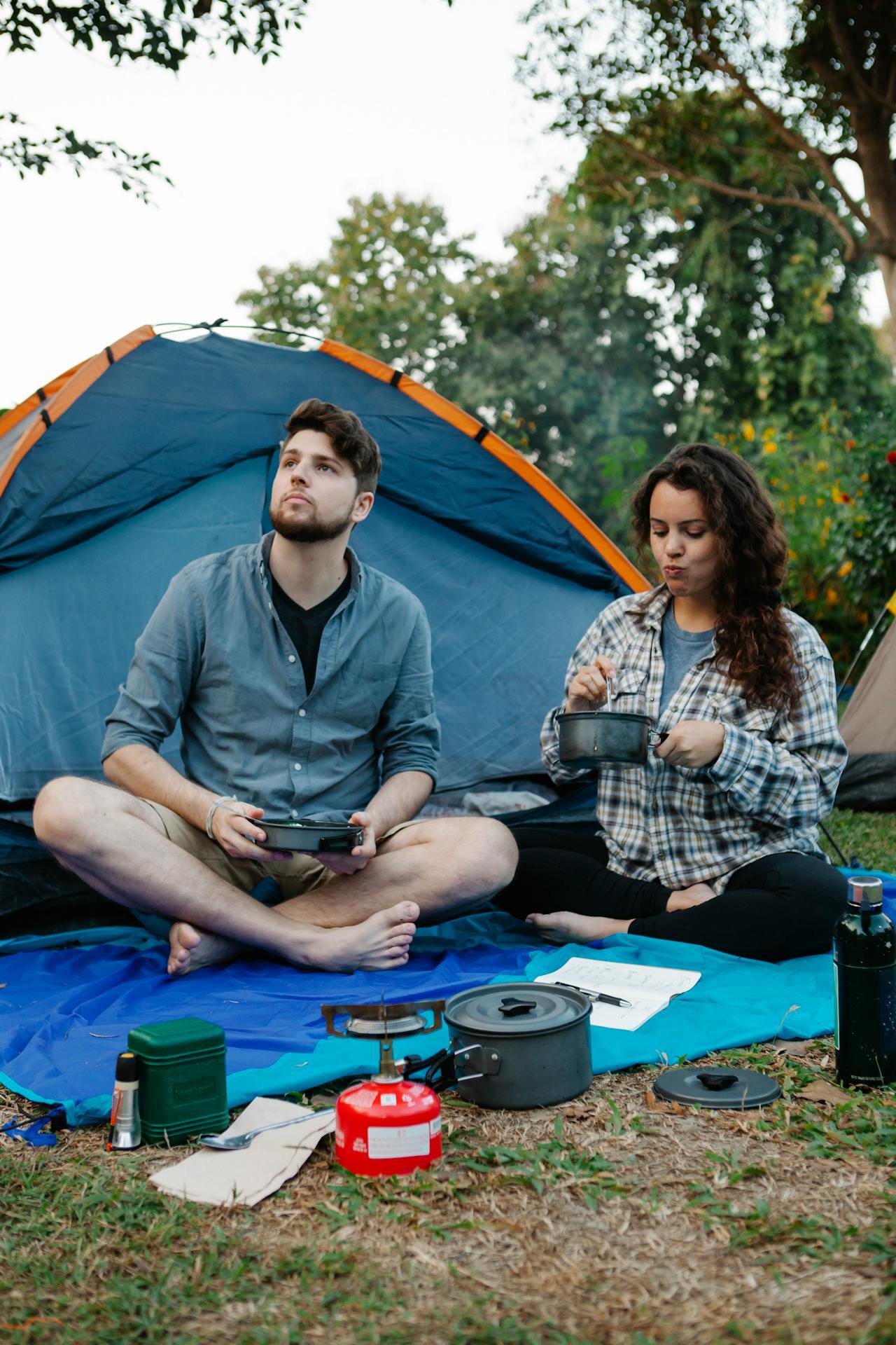 Couple eating food from pots while camping.