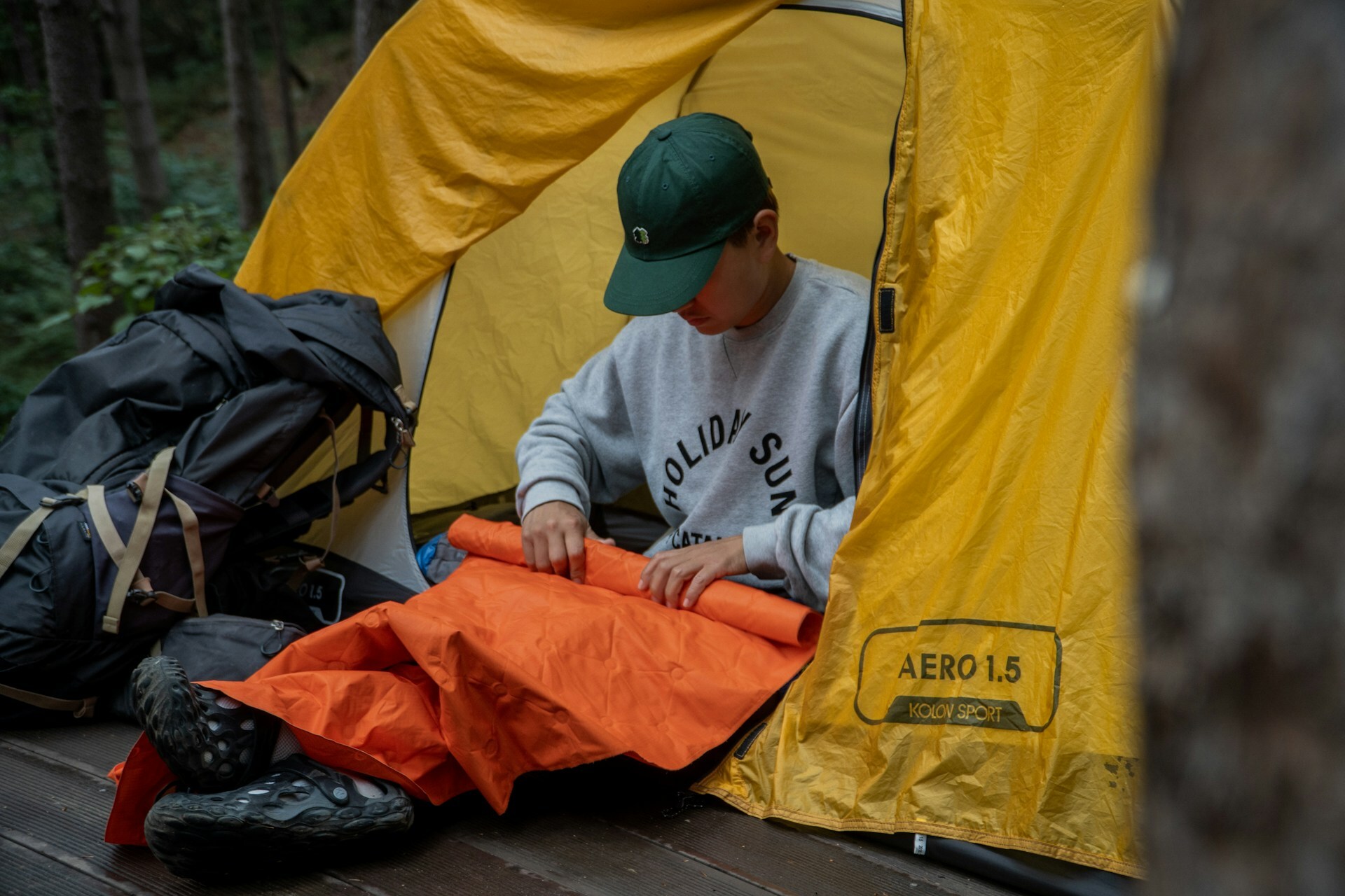 A man rolling a sleeping pad inside a tent A man rolling a sleeping pad inside a tent