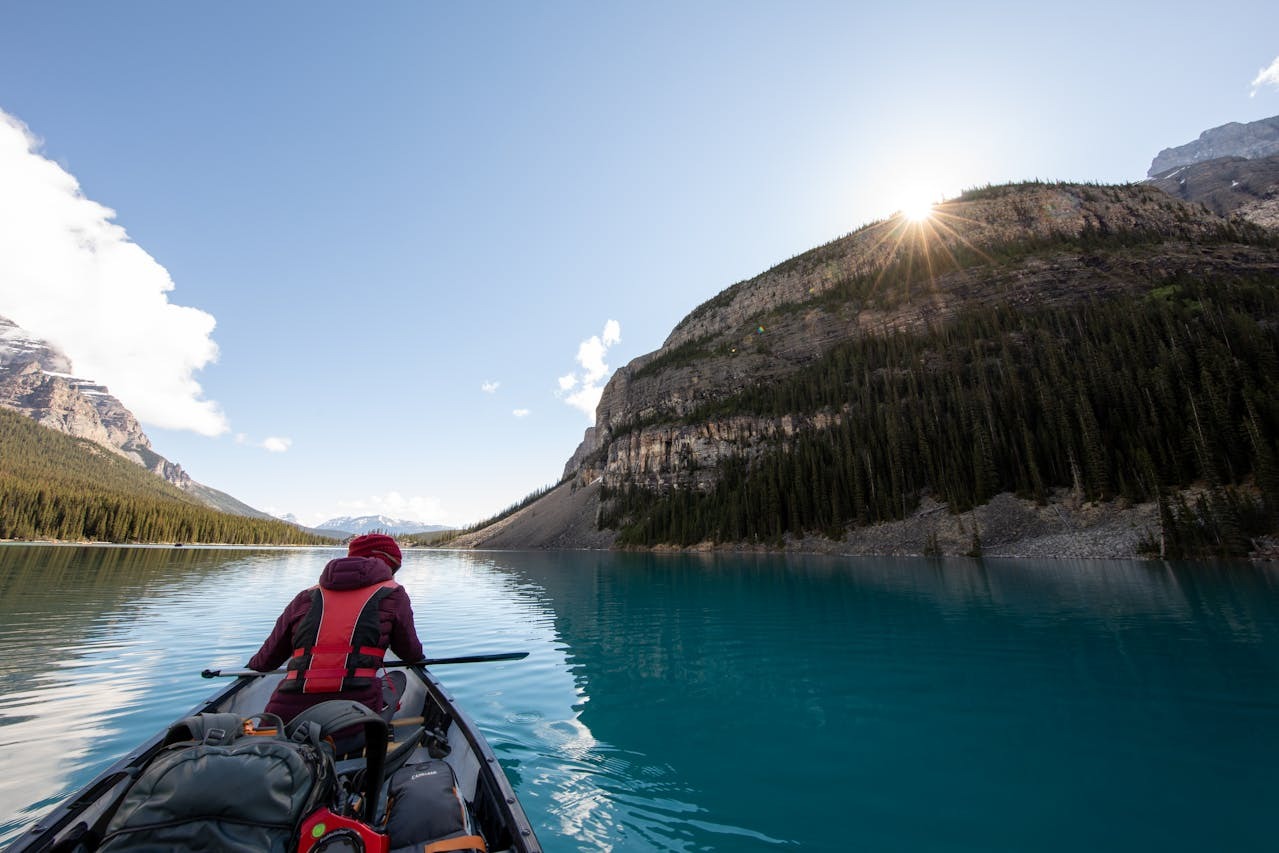 person with camping gear paddling boat