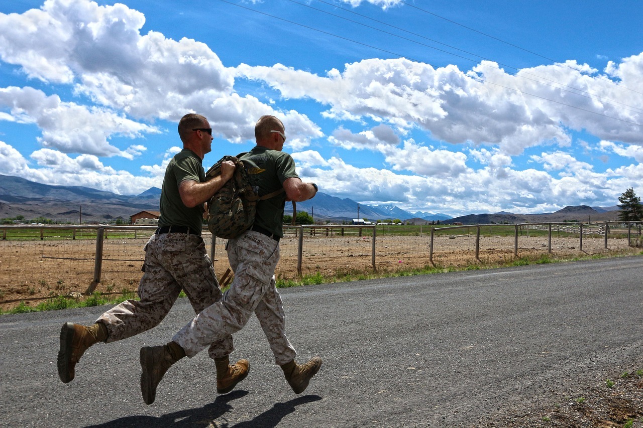 Two soldiers in training running down a road.